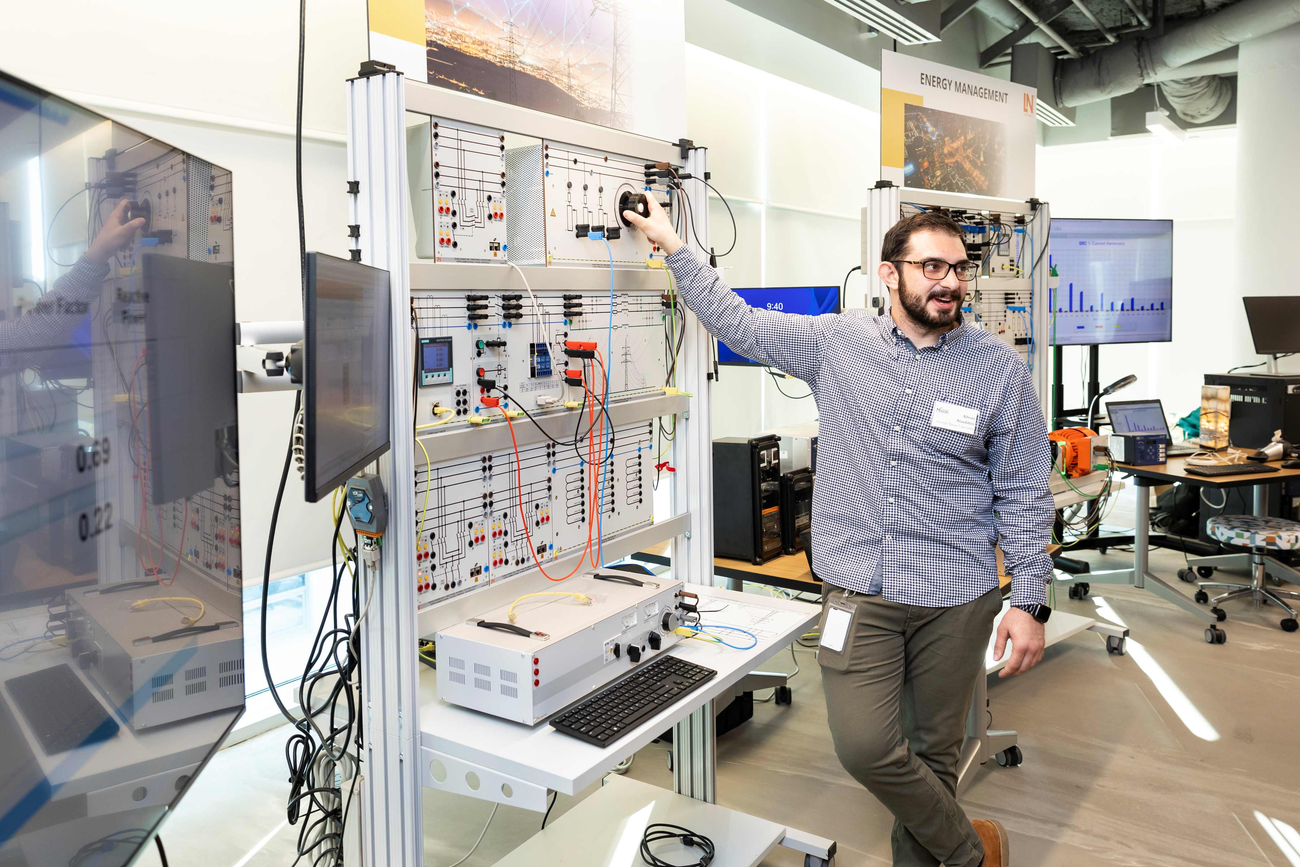 Someone stands in a lab at Fuse and gives a technology demonstration at a circuit board